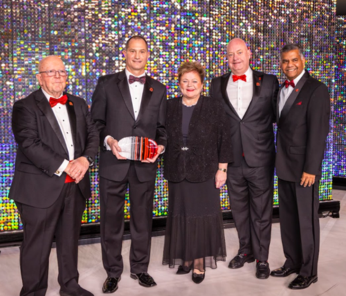 Four men and a woman in black formal wear holding awards.